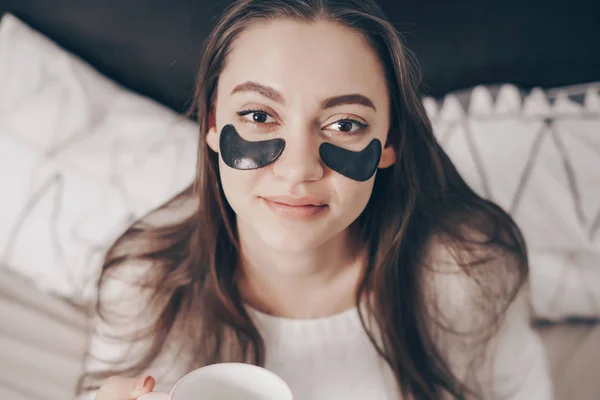 Uma jovem encantadora acordou de manhã cedo de bom humor, sob os olhos de manchas pretas contra o inchaço — Fotografia de Stock