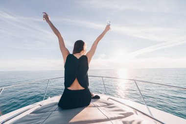 mutlu zengin kız tatil sahiptir, ellerini kaldırdı, deniz manzaralı ve güneş sahiptir