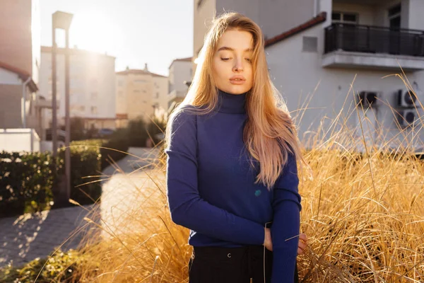 Stijlvolle mooi meisje met lang blond haar, die zich voordeed op de straten van de stad, in trendy blauwe trui — Stockfoto