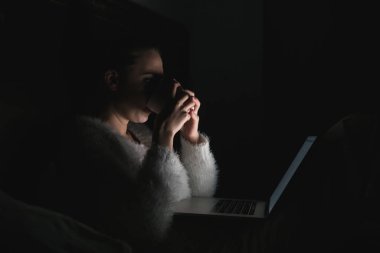 gece geç saatte yatakta oturuyor ve çay, içme kız serbest meslek onu laptop çalışma