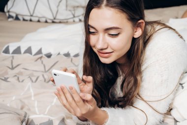 güzel kız yatakta yatıyor ve aittir, onun smartphone bir ileti yazar