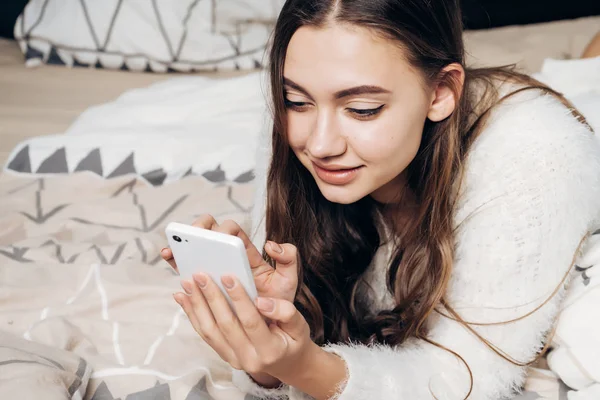 güzel kız yatakta yatıyor ve aittir, onun smartphone bir ileti yazar