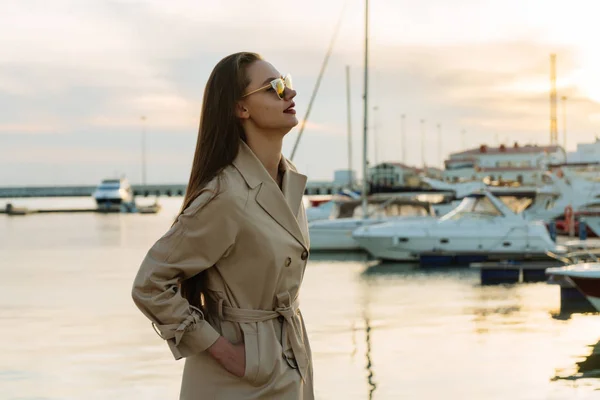 Chica con estilo de confianza con el pelo largo, en gafas de sol esperando un barco en el puerto, por la noche — Foto de Stock