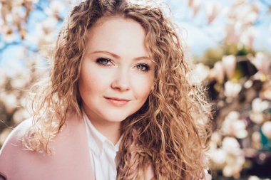 poz ve çiçek açan bir Manolya çerçevede kamera bakarak çekici kıvırcık kadın