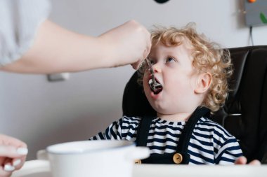 bir tür anne küçük kıvırcık oğlan çocuğunu beslemeleri bir aile akşam yemeği