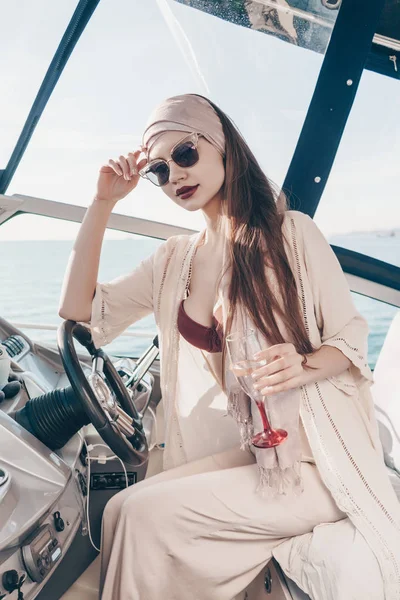 an attractive fashionable girl drinks champagne and drives a ship, a long-awaited vacation