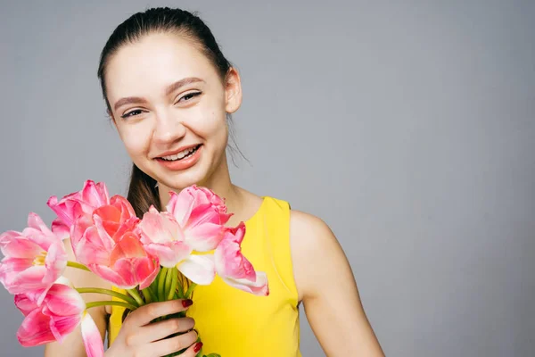 Feliz riendo joven en vestido amarillo sosteniendo un ramo de flores rosadas fragantes — Foto de Stock