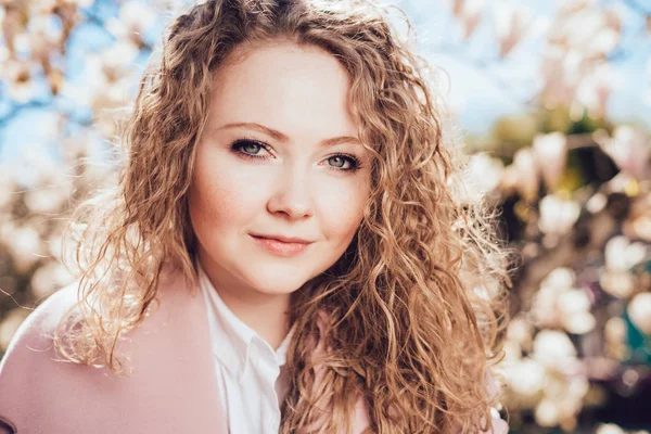 poz ve çiçek açan bir Manolya çerçevede kamera bakarak çekici kıvırcık kadın