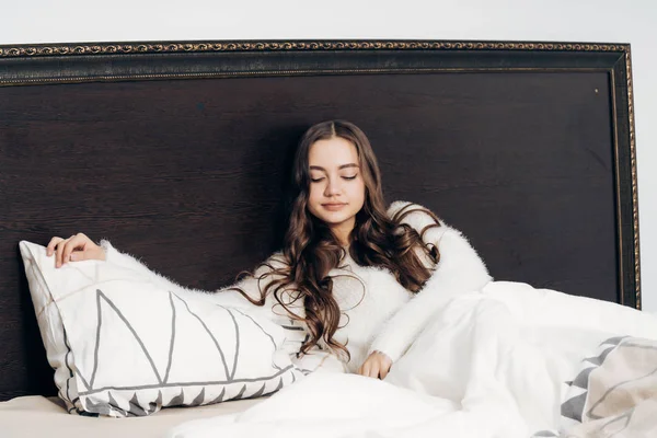Schläfriges junges Mädchen mit langen Haaren liegt im Bett, will schlafen — Stockfoto