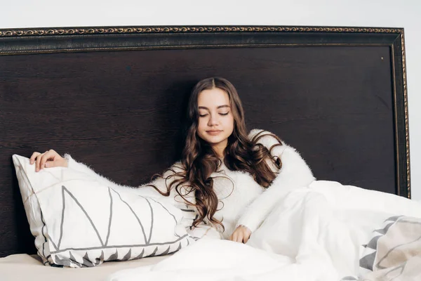 Durmiente joven con el pelo largo se encuentra en la cama, quiere dormir — Foto de Stock