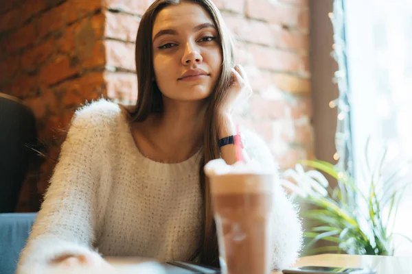 Впевнена красива дівчина фрілансер в білому светрі відпочиває в кафе після роботи — стокове фото