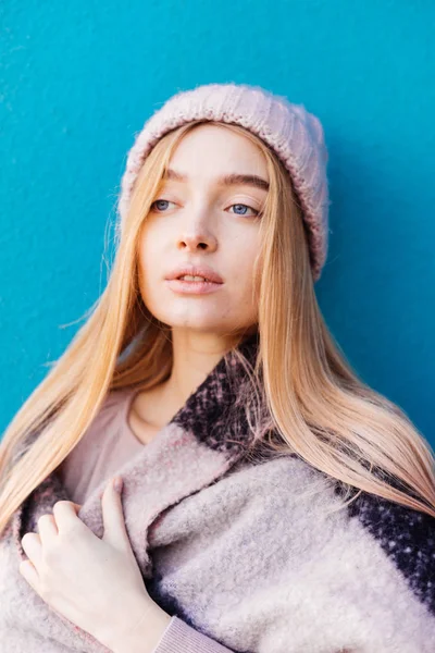 Encantadora chica de ojos azules con el pelo rubio posando contra la pared azul, descansando — Foto de Stock