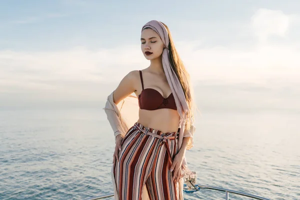 Sexy beautiful girl in fashionable summer clothes rests and relaxes on her yacht, closed her eyes — Stock Photo, Image