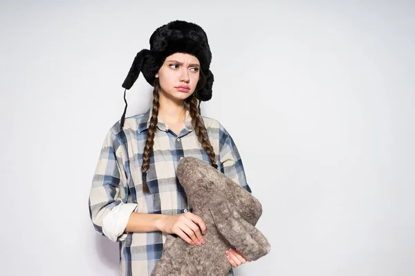 Trauriges, unzufriedenes russisches Mädchen mit schwarzem, warmem Hut wartet auf den Winter, hält graue Filzstiefel — Stockfoto