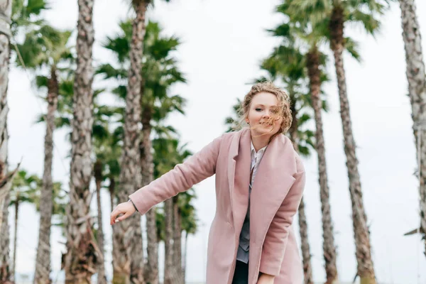 Active stylish girl in a pink coat enjoying a walk through the spring park — Stock Photo, Image