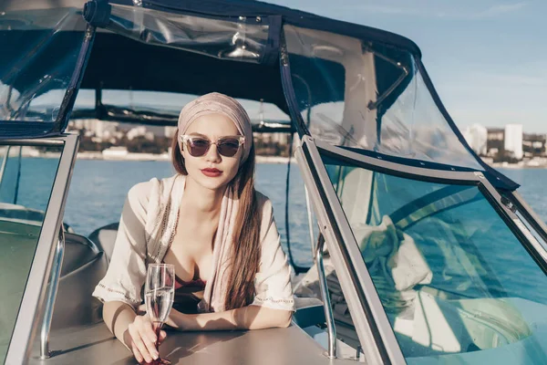 Mujer joven y confiada en gafas de sol nada en un yate blanco, disfruta de una vida rica —  Fotos de Stock