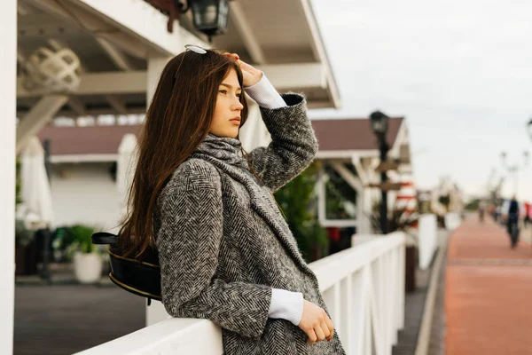 Confiante fille brune en manteau de mode gris se reposant et posant à l'extérieur — Photo
