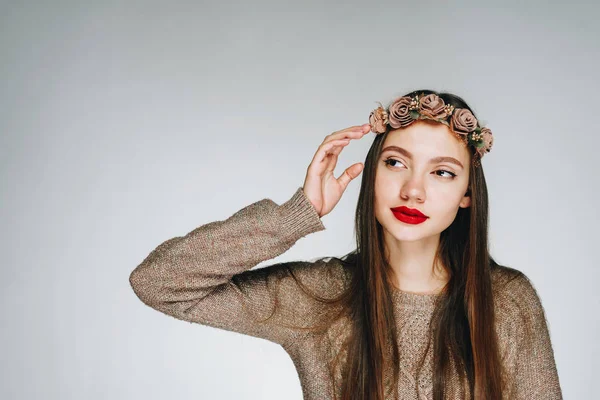 Joven mujer de moda en una corona de flores y con lápiz labial rojo se ve a un lado — Foto de Stock
