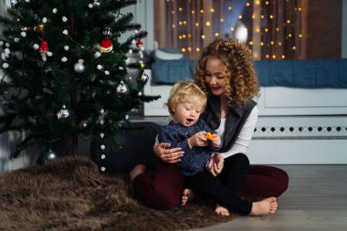 Yeni yıl ve Noel ağacı altında çocuk ile Genç Anne çalış