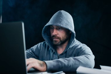 Deneyimli bir hacker bir dizüstü karanlık bir odada arkasında çalışır
