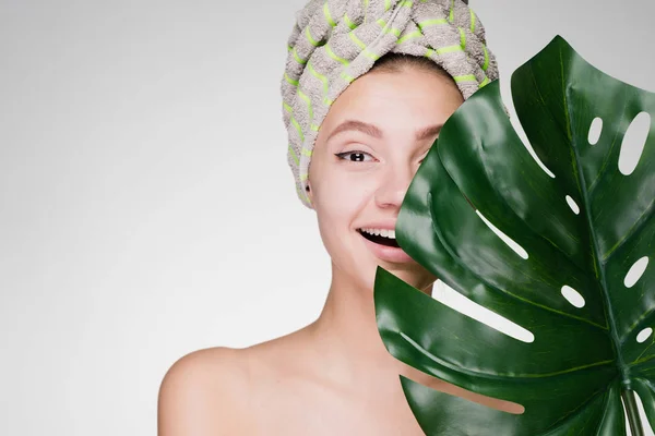 Kobieta, trzymając ręcznik na głowie, posiadający duży liść — Zdjęcie stockowe