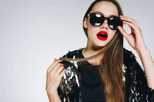 Young stylish woman in a brilliant jacket holding dark sunglasses, mafia — Stock Photo, Image