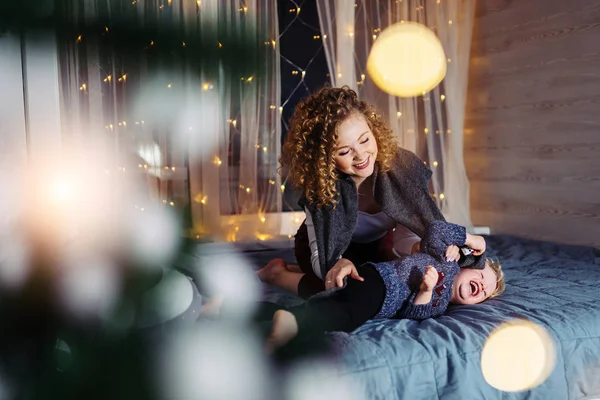 Madre e hijo juegan en la cama, ríen y disfrutan de las vacaciones — Foto de Stock