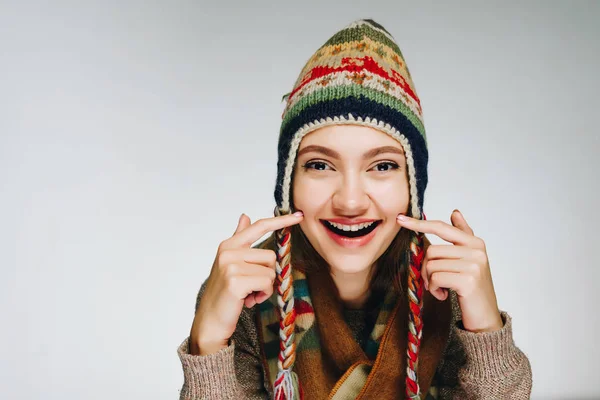 Junge, fröhliche Frau mit skandinavisch warmer Mütze und Schal auf weißem Hintergrund zeigt gesunde Haut — Stockfoto