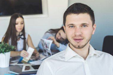 Genç bir adam bir masada oturan iki kız önünde duruyor