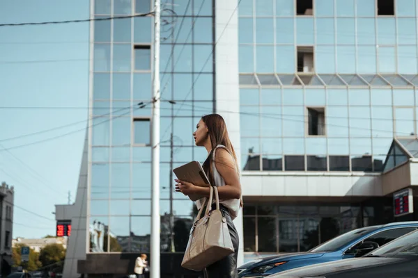 Модная женщина в офисной одежде идет по улице на фоне стеклянных офисных зданий — стоковое фото