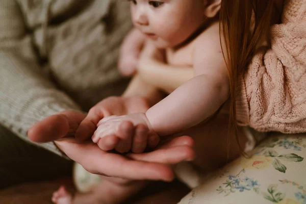 La mano grande del padre sostiene una pequeña pluma de un hijo recién nacido — Foto de Stock