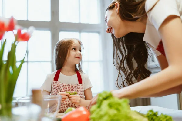 Mamá e hija cocinan juntas, se miran y sonríen, el día de la madre — Foto de Stock