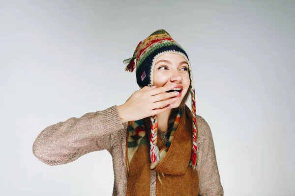 Funny girl in winter clothes with patterns makes a face and touches her nose — Stock Photo, Image