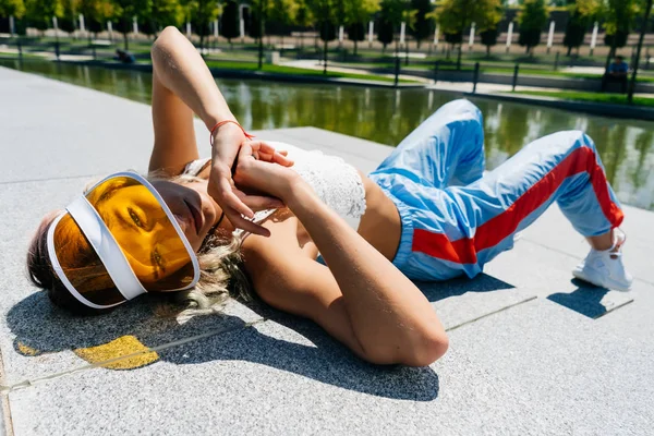 Sport mode meisje liggend in het Park op de grond en kijken naar de camera — Stockfoto