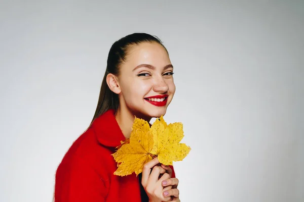 Dziewczyna w czerwonej marynarce śmieje się i trzyma Bukiet żółtych jesiennych liści — Zdjęcie stockowe