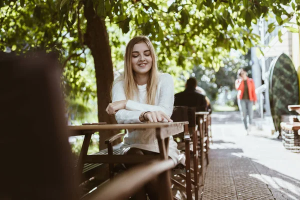 Una ragazza si siede in un caffè di strada e aspetta qualcuno . — Foto Stock