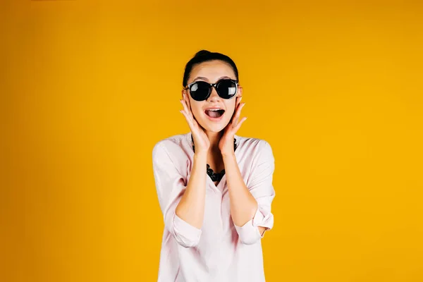 Chica sorprendida en gafas redondas negras sobre un fondo amarillo — Foto de Stock