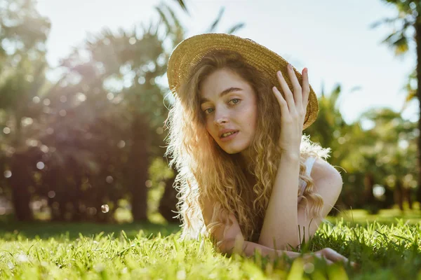 Göndör lány feküdt a fűben az árnyékban és pihenés. Nyári portré a fűben — Stock Fotó