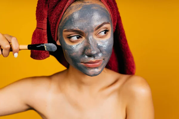 Ragazza applica una maschera magnetica sul suo viso con un pennello — Foto Stock