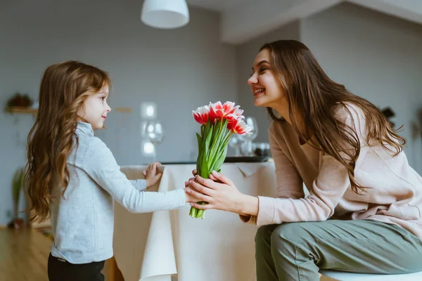 A kislány ad egy csokor friss rózsaszín tulipánt az anyjának. — Stock Fotó