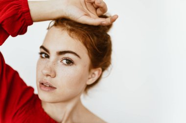 Stüdyodaki kırmızı bluzlu genç kız, elini alnına koydu.