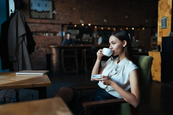 Chica bebe café en un café sentado en una silla —  Fotos de Stock