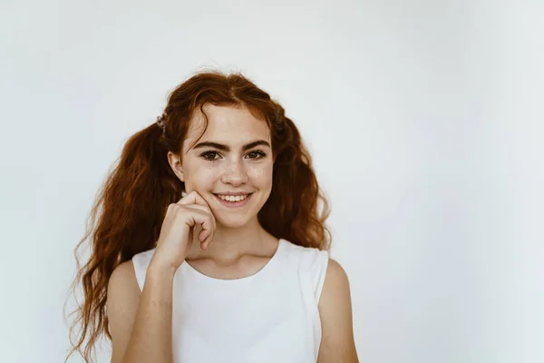 Colegiala con coletas sonriendo se sostiene por la mejilla — Foto de Stock