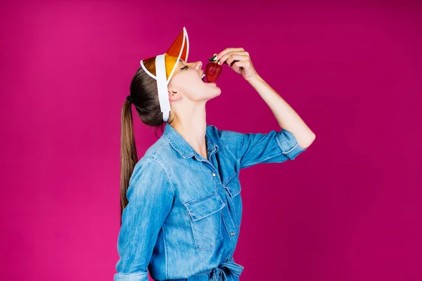 Studio rose. la fille dans le pic met ludique fraises dans sa bouche — Photo