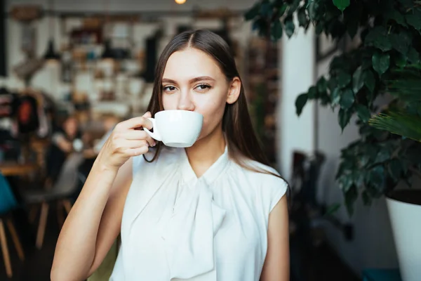 student drinks coffee on the background of the interior of a cafe or library