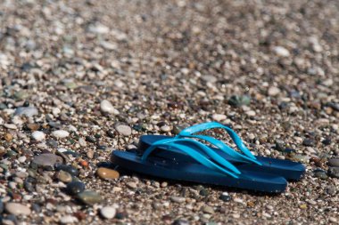 küçük çakıl, kum üzerinde lastik sandaletler ile plaj