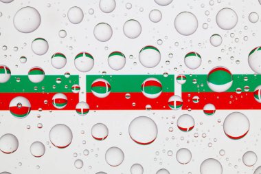 Yağmur damlaları ile kaplı bir cam arkasında Bulgaristan bayrakları.