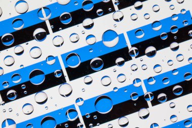 Estonya bayrakları bir cam arkasında yağmur damlaları ile kaplı. Estonya bayrakları desen