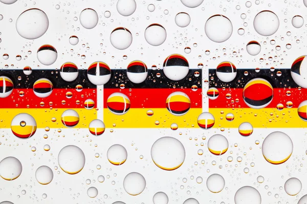 Flags  of Germany behind a glass covered with raindrops.