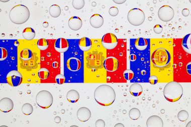 Yağmur damlaları ile kaplı bir cam arkasında Andorra'nın bayrakları.